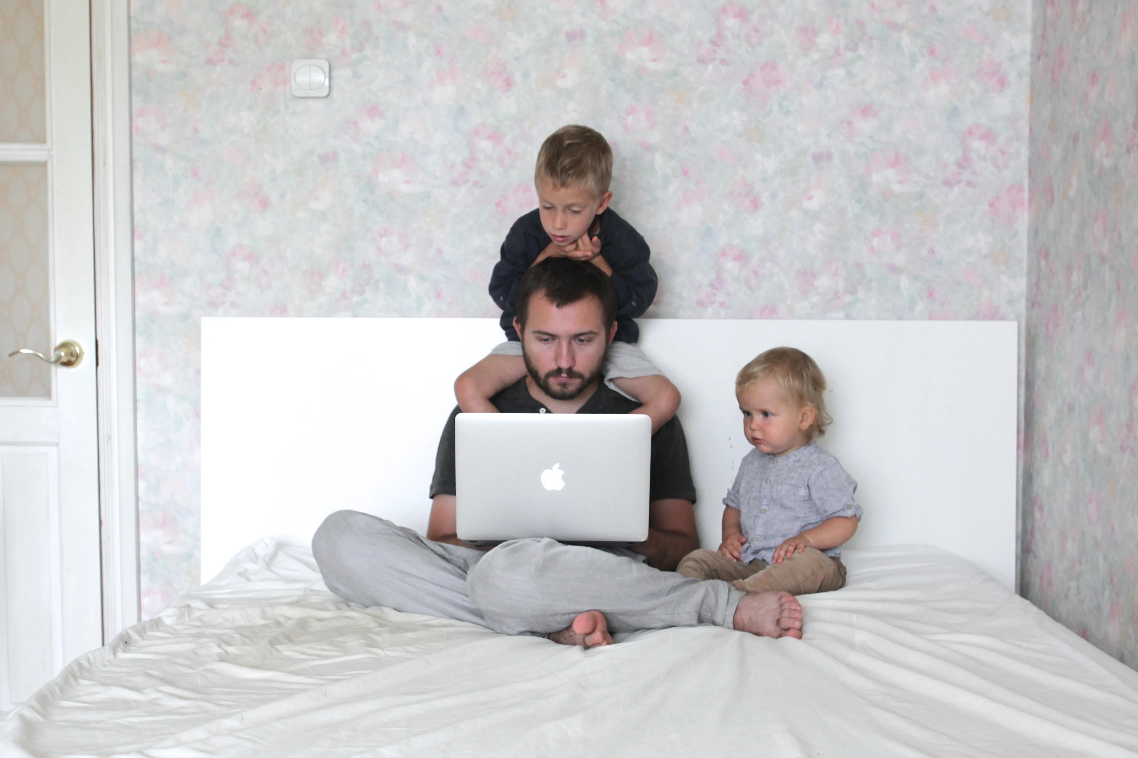 Father working on the laptop in bed with his sons